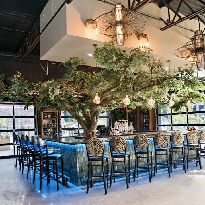 Custom tree centerpiece surrounded by an illuminated tiled bar and oyster-inspired seating at Blake’s Oyster Bar in Atlanta